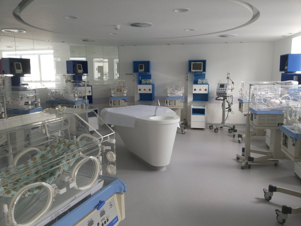 Modern neonatal intensive care unit with incubators, medical equipment, and monitors in a clean white room